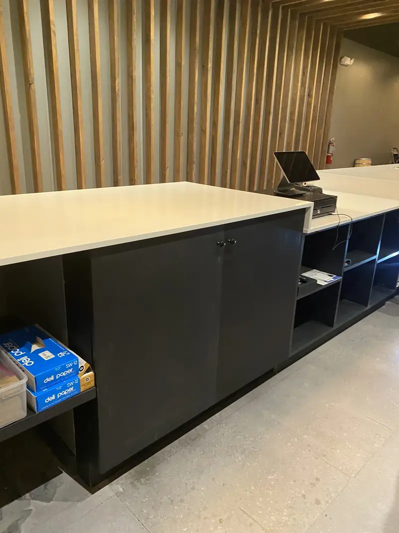 Commercial counter with dark cabinetry and a vertical wood-slat wall by Eco Woodwork & Design